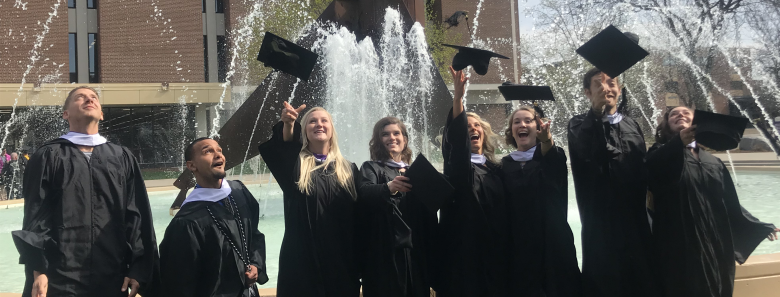 a group of women in graduation gowns throwing caps in the air