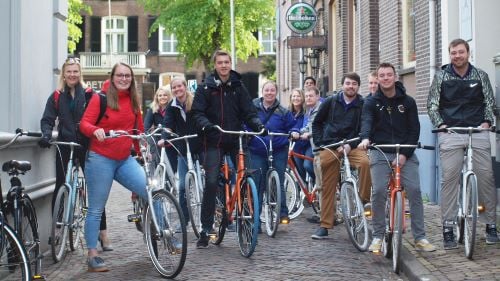 Sport Management students and professor posing outside on bicycles while on a study abroad trip
