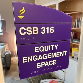 Purple sign that says "CSB 316 Equity Engagement Space" on the window outside of the entrance