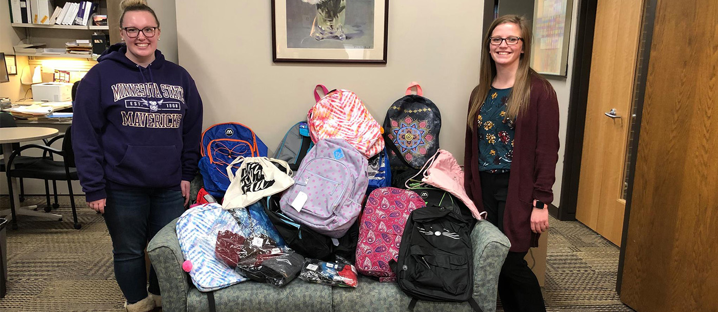 Two BSSW child welfare students with backpacks that are going to be donated to childrens in need