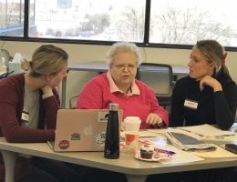 Two students working with an elderly woman during an adult language and cognitive impairment session