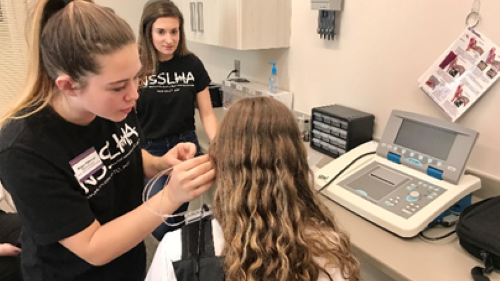 Students demonstrating audiology equipment for high school students