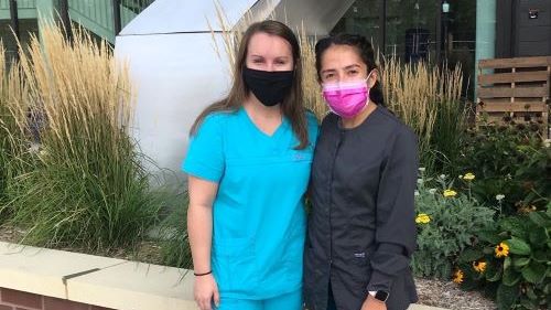 Kaitlyn Knutson and Lissette Garza outside the Clinical Sciences Building in scrubs and masks