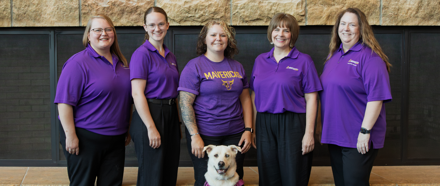 Group of people wearing purple shirts with a dog in the foreground
