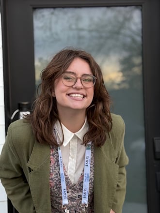 Smiling woman with glasses standing in front of a glass door