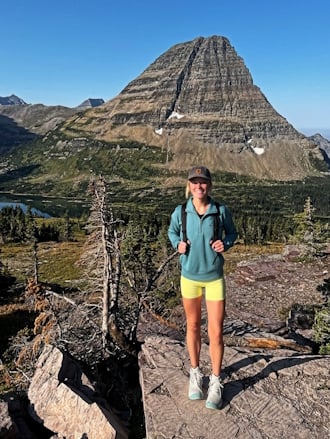 Woman in hiking gear standing on a rocky landscape with a mountain in the background