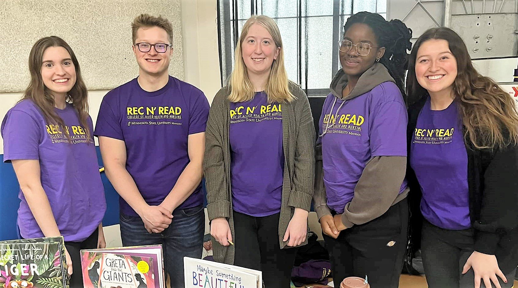 Five students in purple Rec N' Read tshirts with books