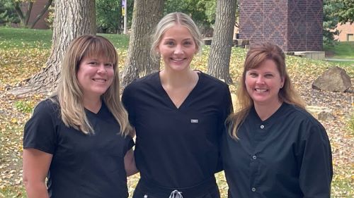Three Advanced Dental Therapy students outside on campus in scrubs