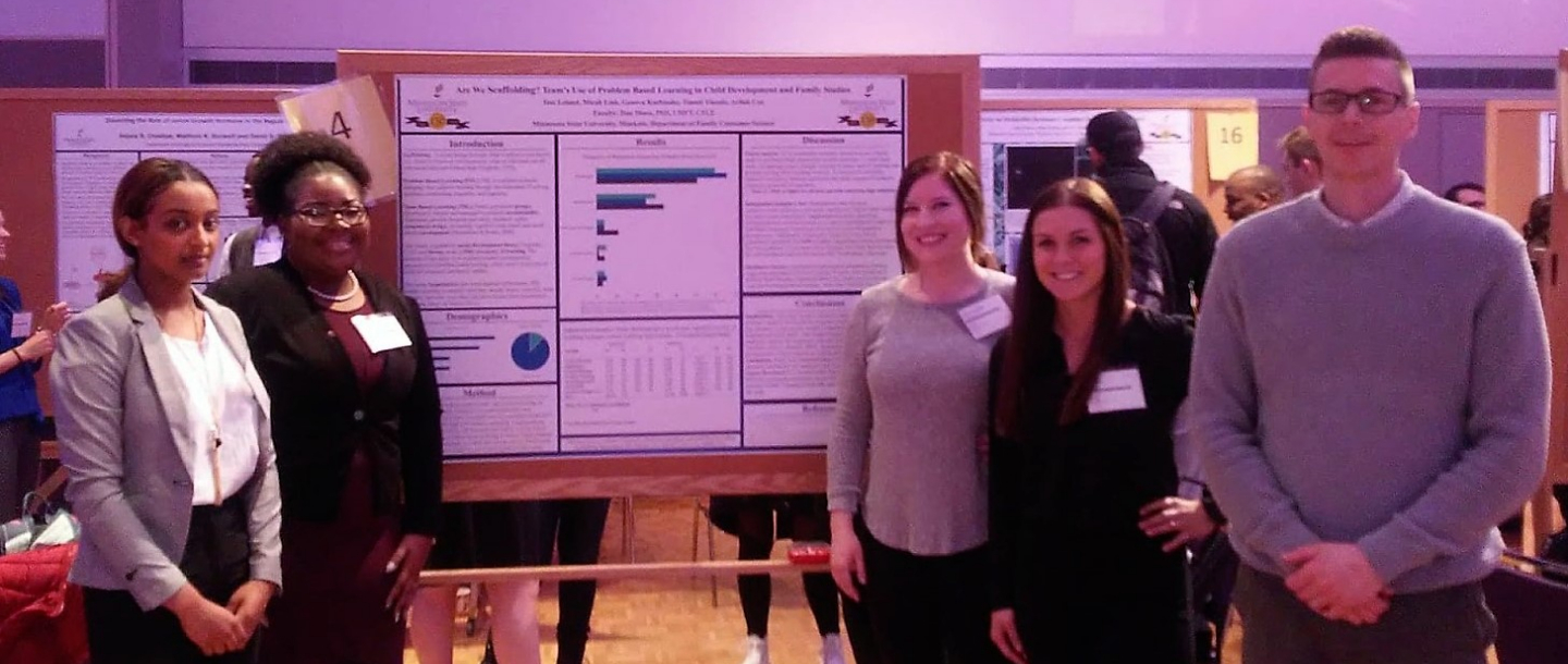 Students and faculty standing by a Child Youth and Family research poster