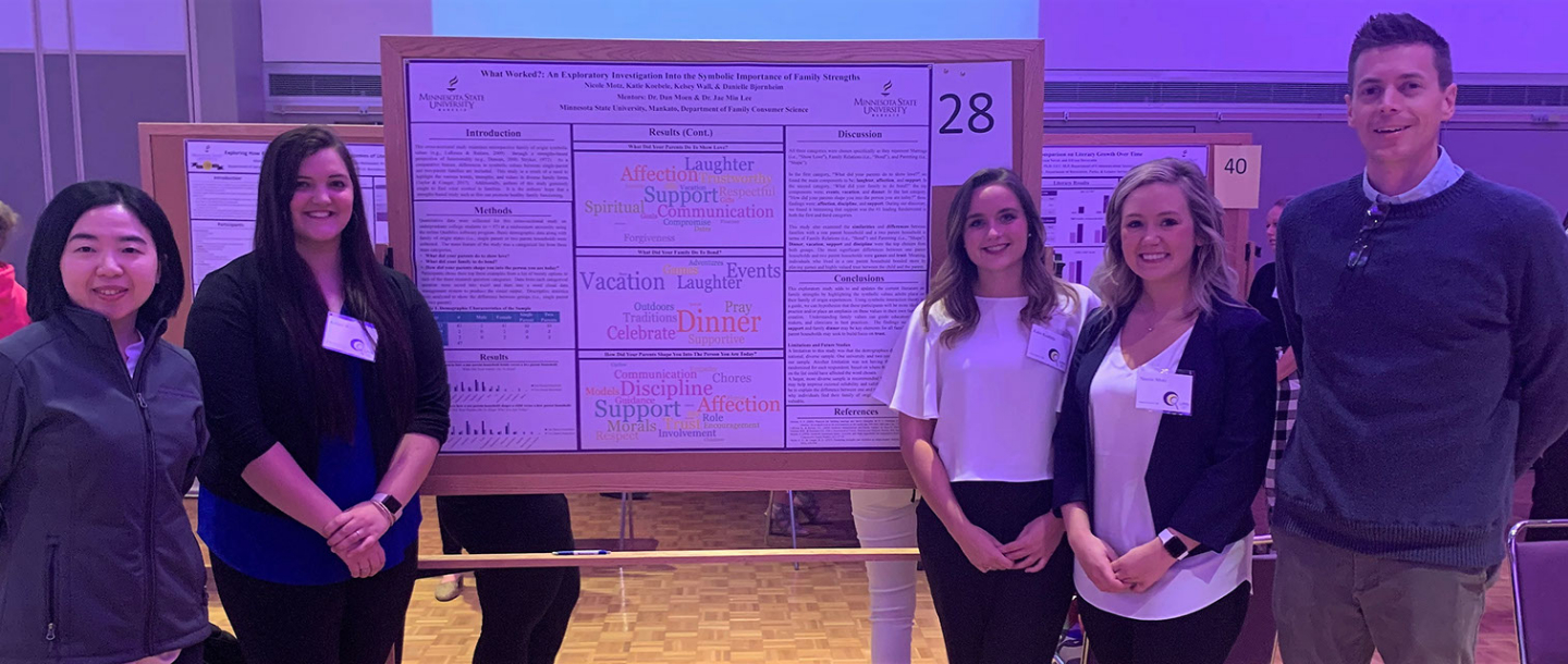 Students and faculty standing by a research poster 