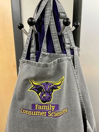Family Consumer Science branded aprons hanging on a hook