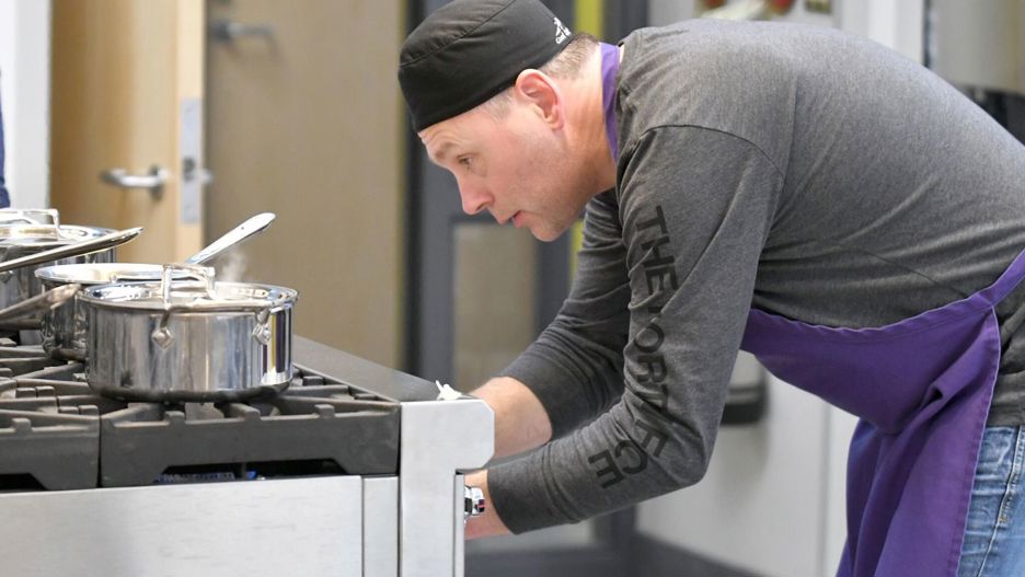 A dietetics student checking the pots on the stove in the food lab