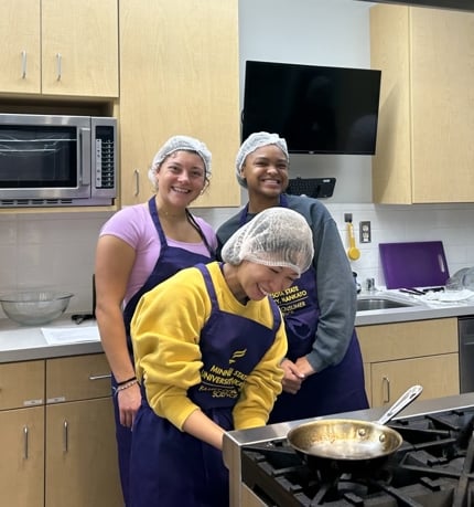 Three students cooking in a classroom