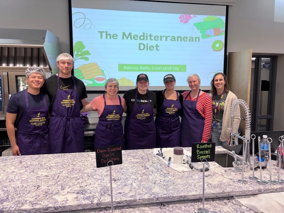 Group of students standing in front of a screen that says 'The Mediterranean Diet'