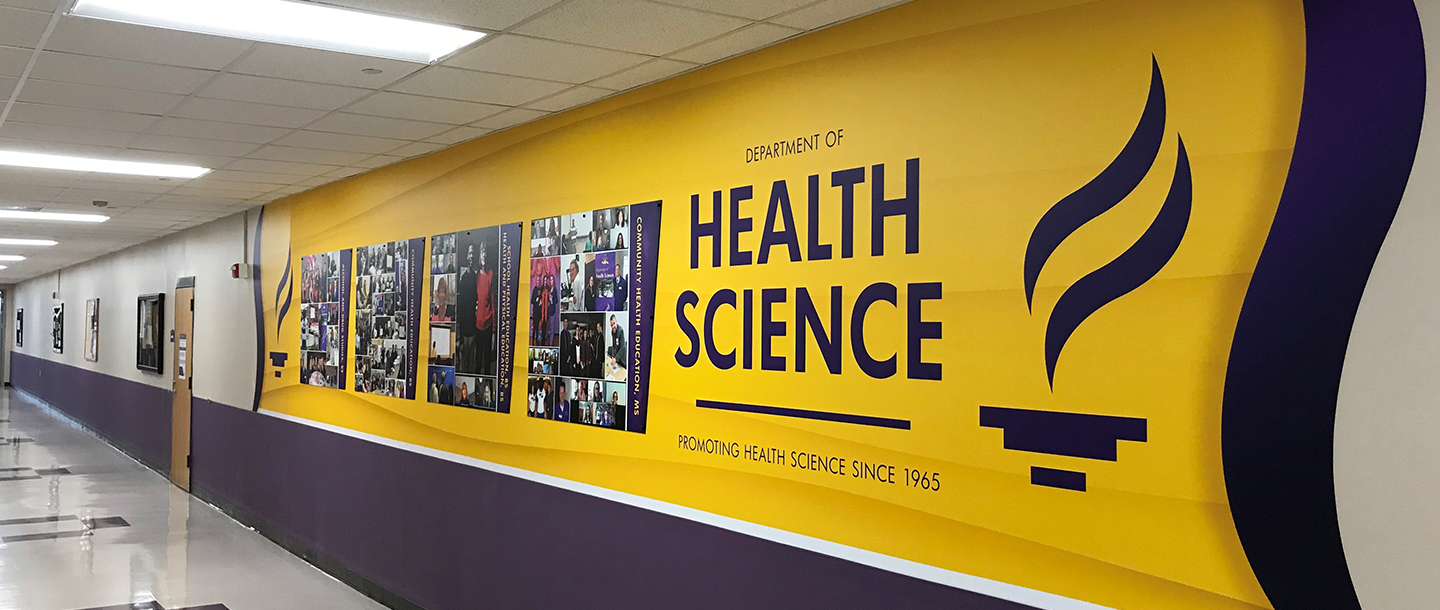 The Department of Health Science Promoting Health Science Since 1965 logo displayed on the wall in the hallway next to the department office