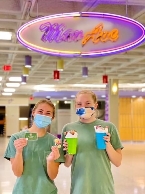 two women wearing face masks holding food and smiling