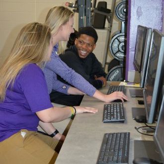 Three Health and Physical Education students working together in the computer lab