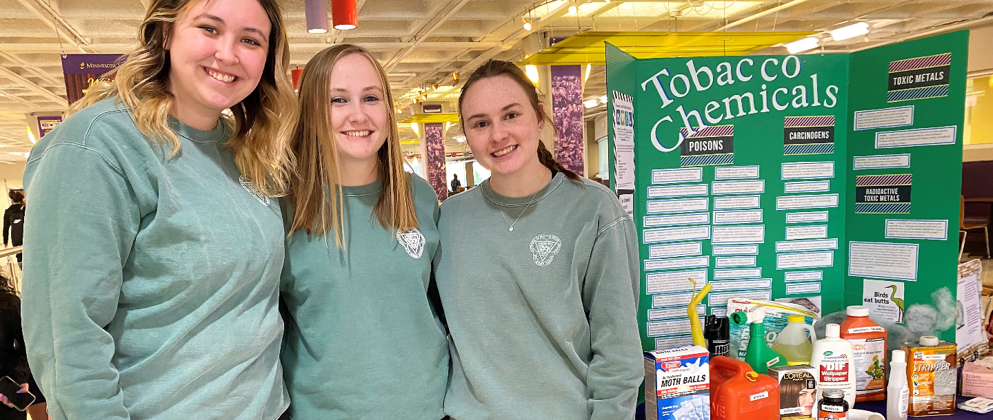 Three students providing health education about tobacco chemicals