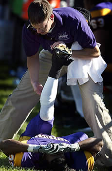 Athletic trainer stretching athlete's leg