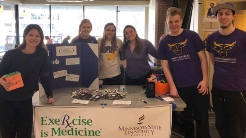 A group of Exercise Science students posing by their exercise is medicine table in the Centennial Student Union 