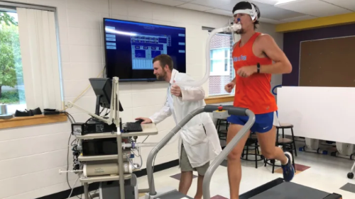 A student on a treadmill hooked up to a breathing machine while another student is checking the data on a computer