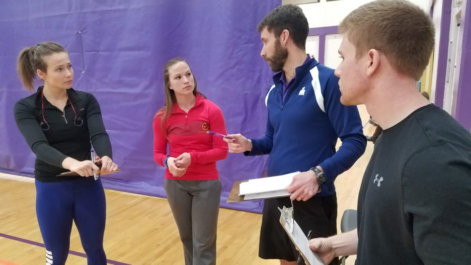 Faculty talking with students before a physical education and DAPE activity in the gym