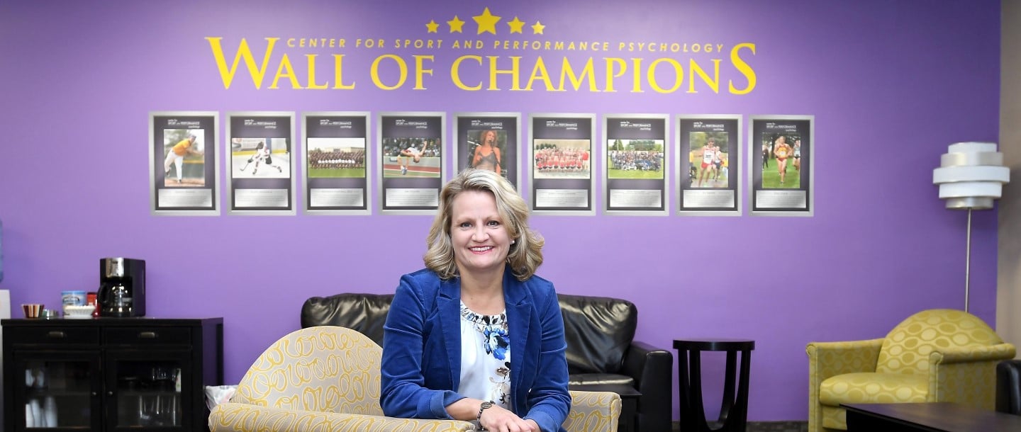 Dr. Cindra Kamphoff, Sport and Exercise Psychology Program Coordinator posing in front of wall of champions