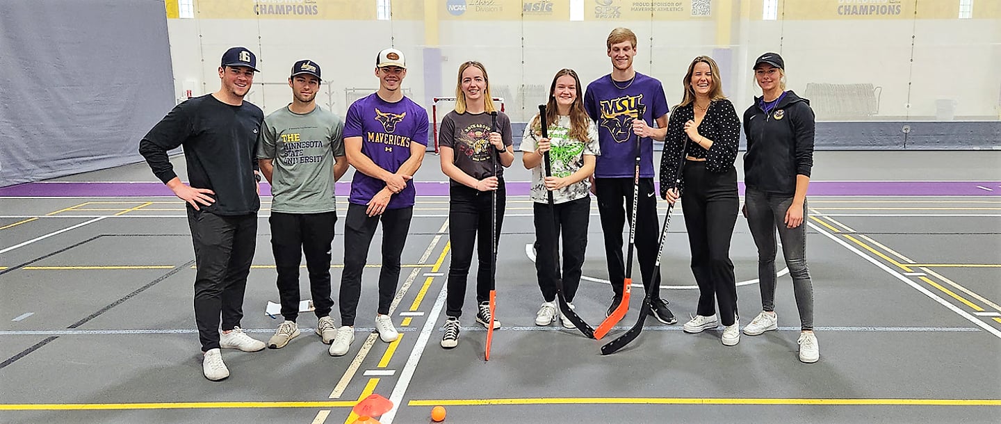 A group of students posing with hockey sticks in Myers field house