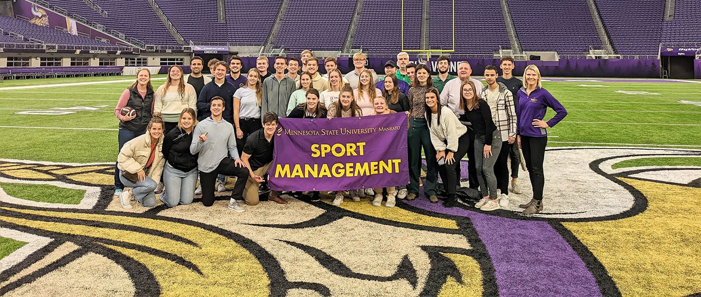 A large group of Sport Management students on the field of the US Bank Stadium