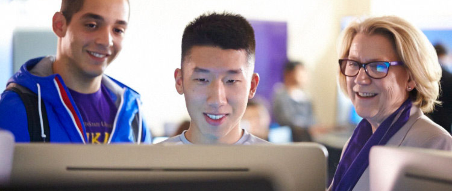 Two students with Dean of College of Allied Health and Nursing looking at something in the computer