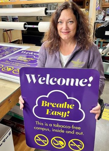 Faculty member holding a sign that says "Welcome Breathe Easy"