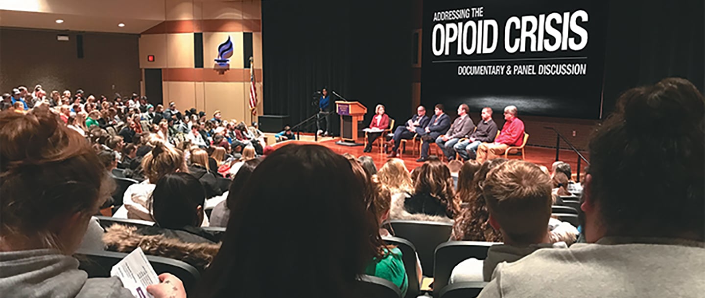 A documentary and panel event addressing the Opioid crisis with the panel sitting on the stage in an auditorium