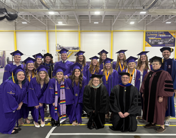 A group of graduating students and professors at a college in the field house.