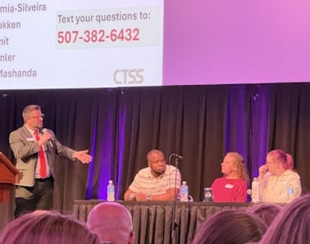 Presenter speaking with a panel of people on stage