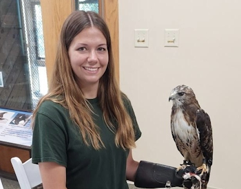 Smiling woman holding a large bird with a special glove