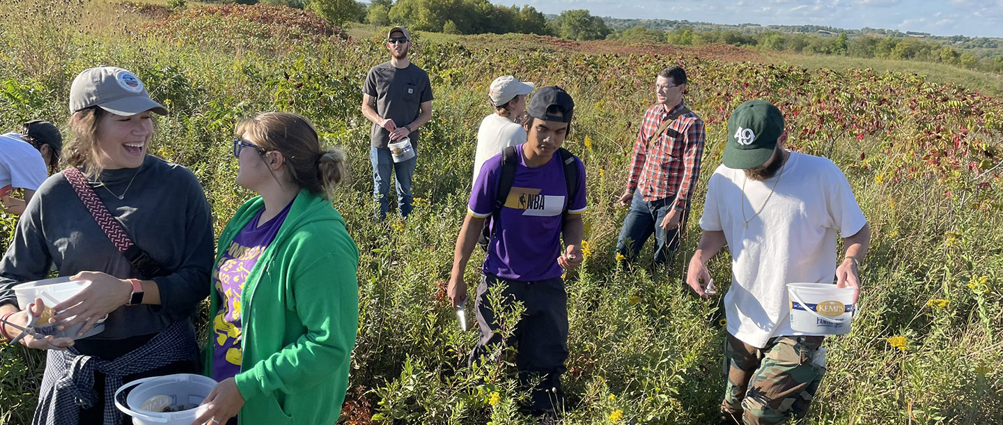 Recreation and Parks Leadership Studies students picking berries outside in a field during a class activity