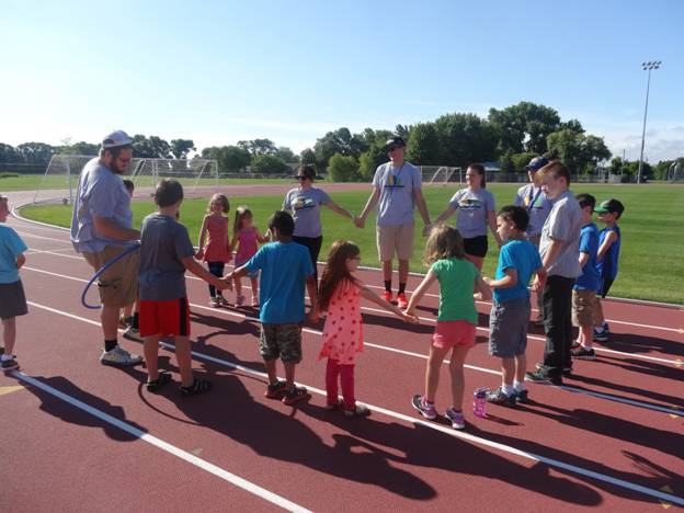 RPLS students with kids doing an activity on an outdoor track 