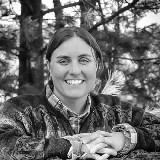 Black and white profile photo of Alli Faricy posing outside with a smile and trees in the background
