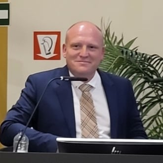 Profile photo of Dr. Dennis Demedts standing at a podium