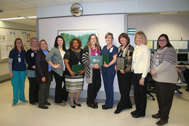 Several nurses and faculty in a clinical setting holding documents