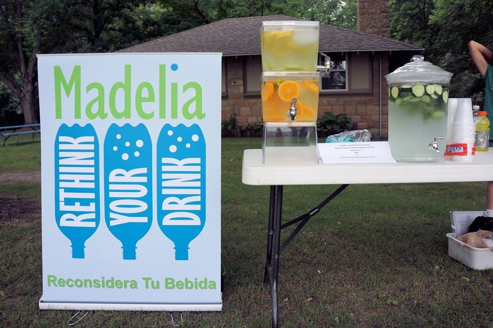 An exhibit with fruit and vegetable infused water on the table and a sign that says Rethink Your Drink