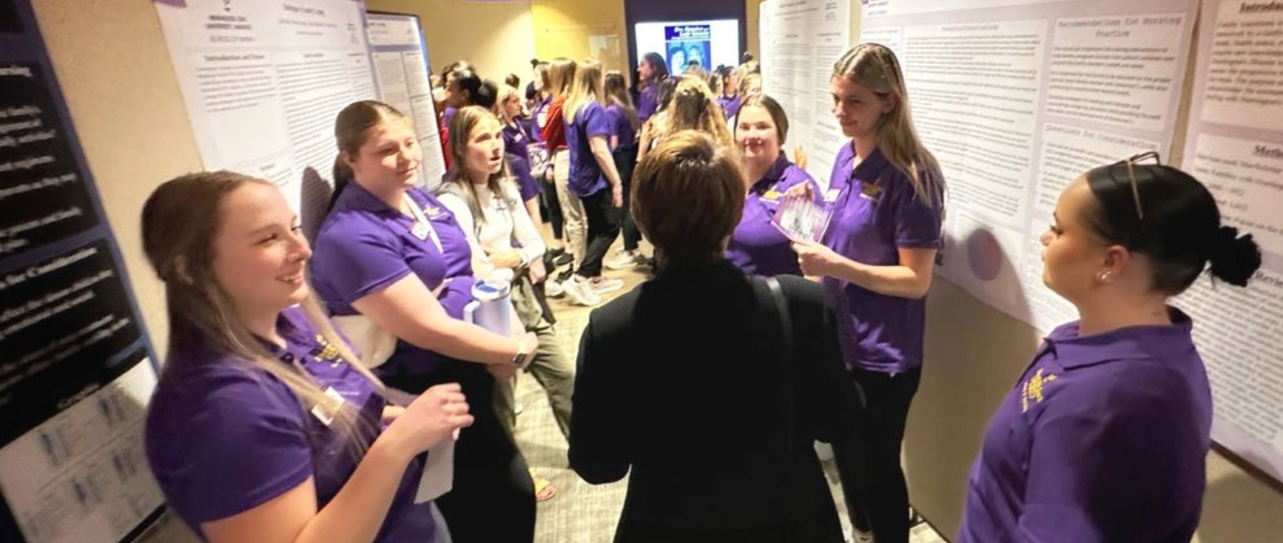 Several nursing students in a row, displaying their research.