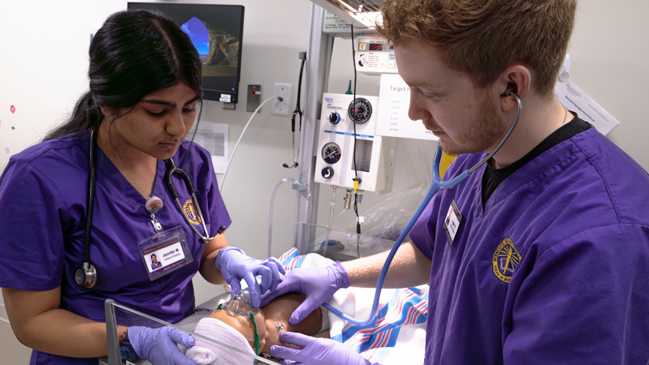 a person and person in purple scrubs and purple gloves working on a baby