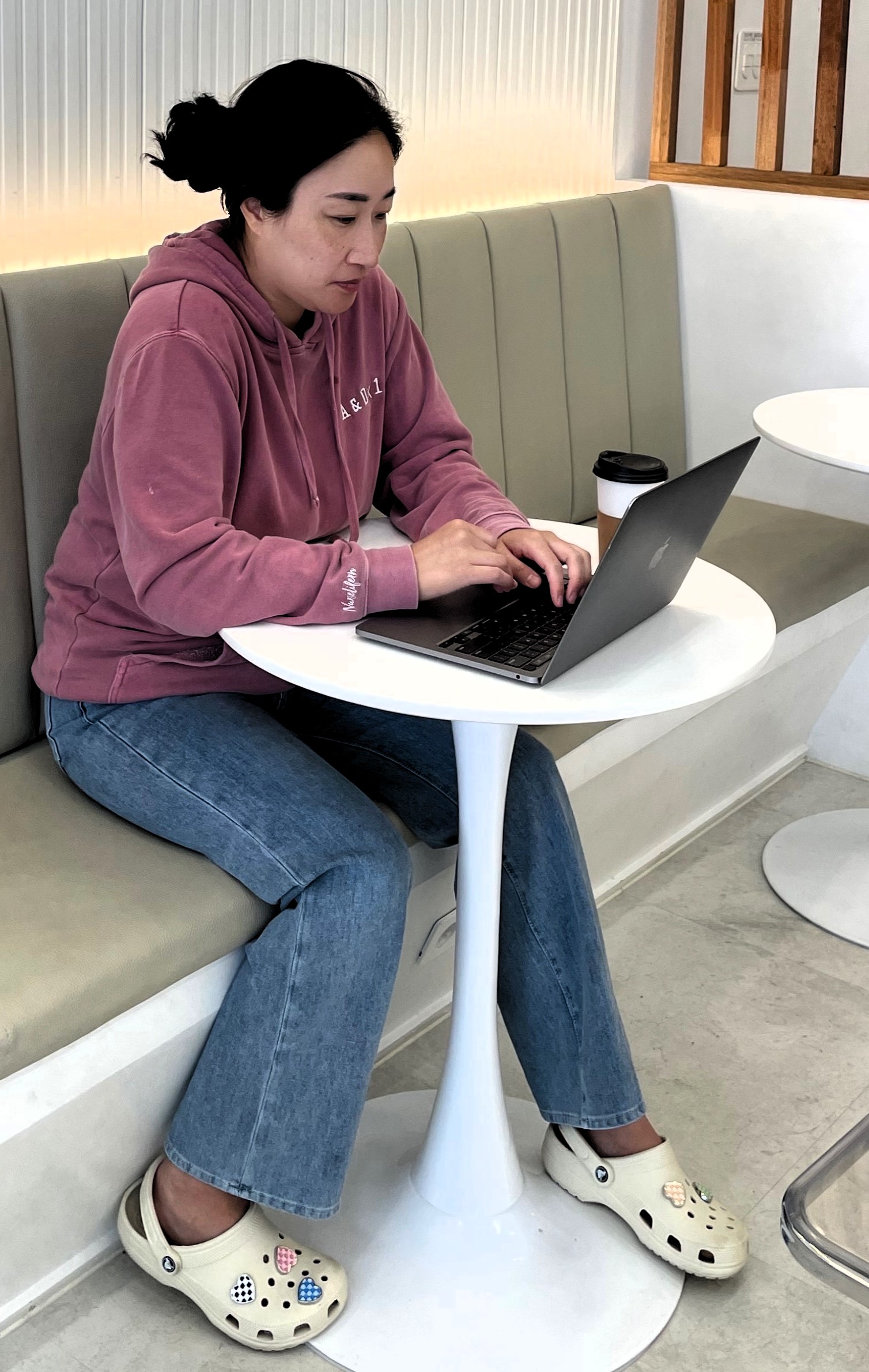 Hyeju Dorek sitting in a coffee shop working on a laptop.