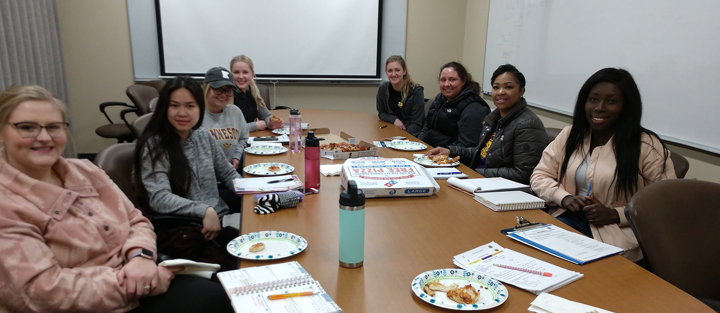 Eight BSSW child welfare students taking pizza break while on group meeting 
