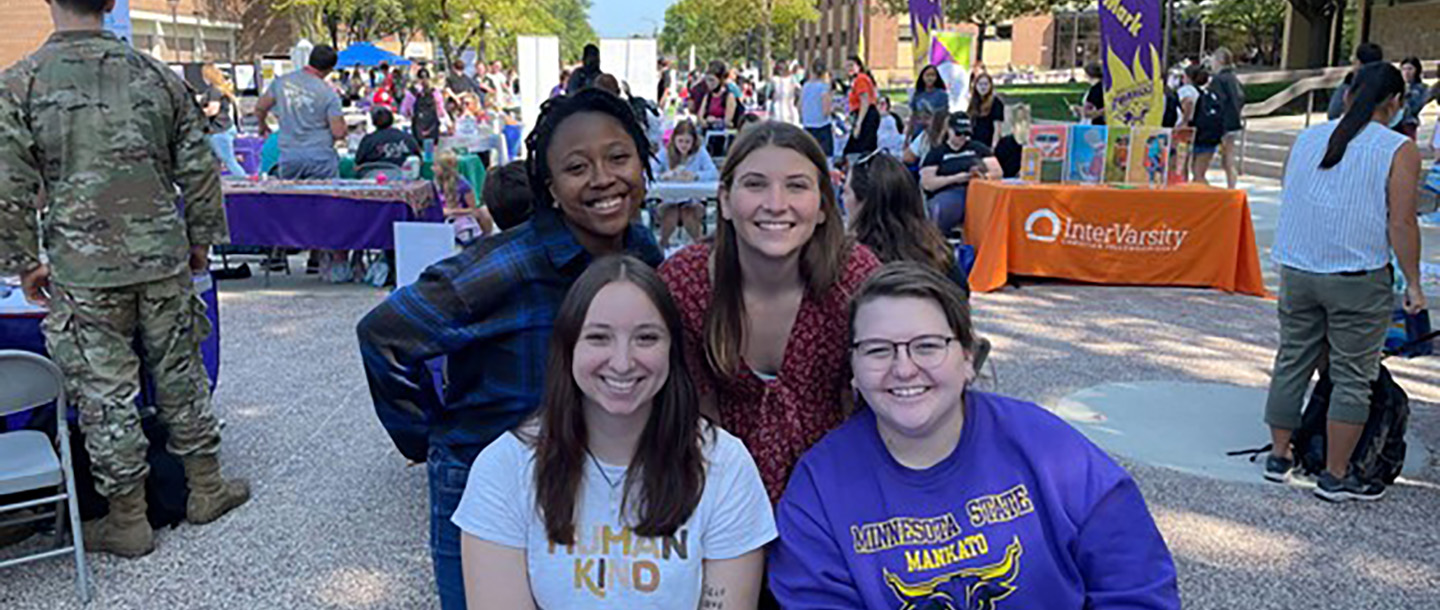 Four students at campus organization fair outside on mall area