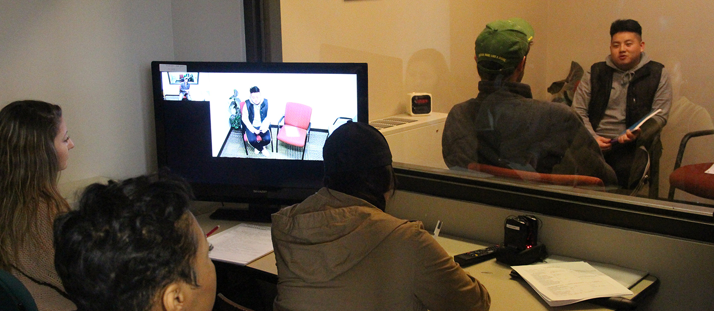 Three Social Works students observing a real time interview on a monitor