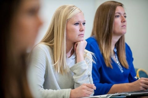 Three women at a table listening and taking notes