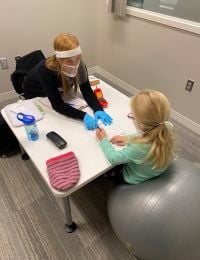 A student working with a child during a speech disorders session with kid activities