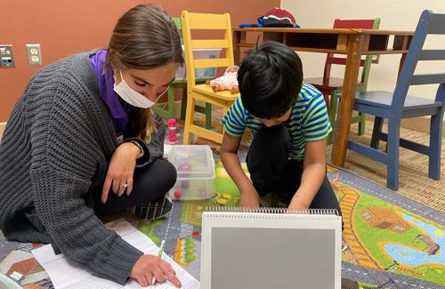 Nursing student practitioner on floor with a child client at the Pond clinic